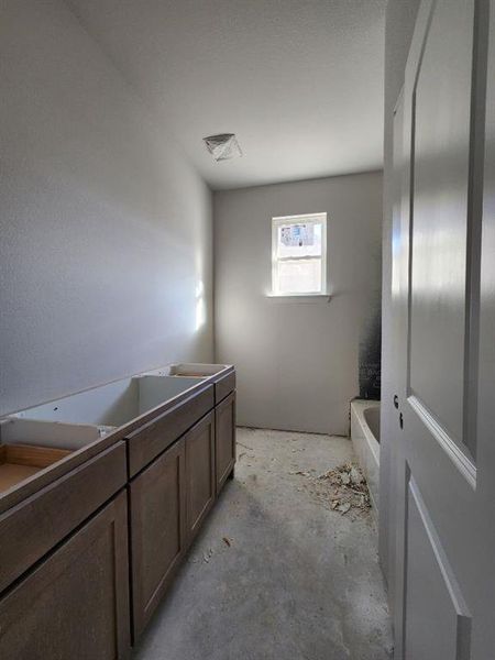 Full bathroom with vanity, unfinished concrete floors, and a bathtub