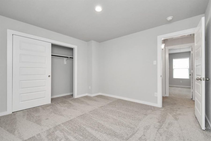 Secondary bedroom with neutral paint, plush carpet, and large windows for natural light.