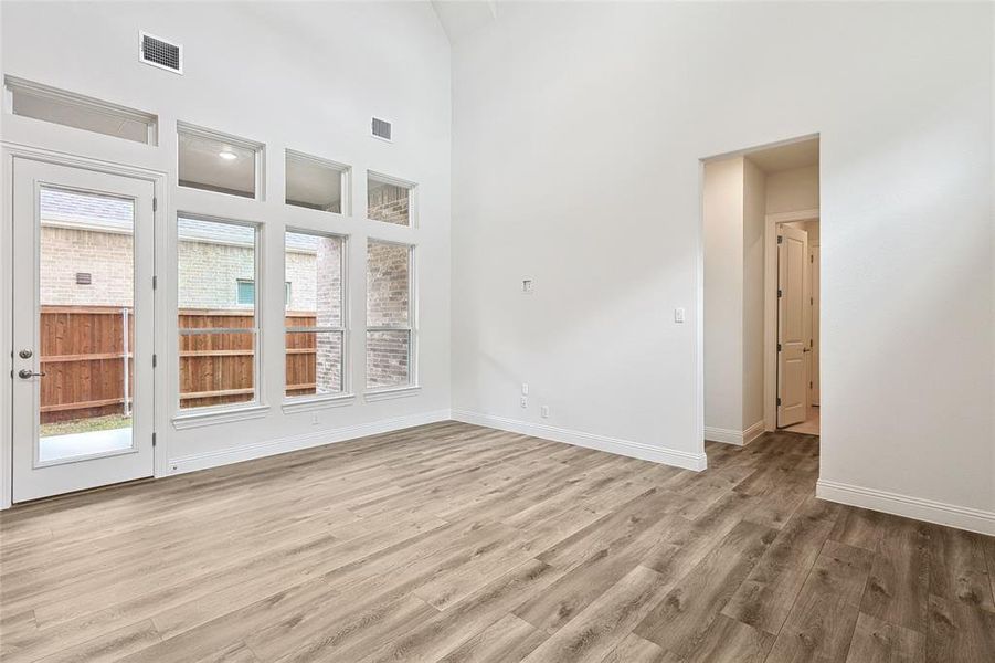 Spare room with a towering ceiling and light wood-type flooring