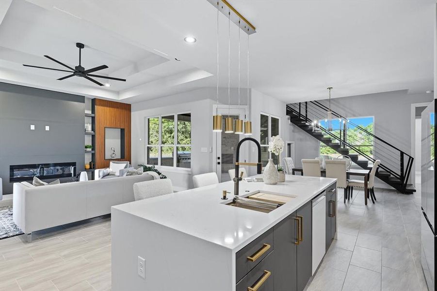 Kitchen with a glass covered fireplace, a tray ceiling, an island with sink, hanging light fixtures, and modern cabinets Kitchen with a glass covered fireplace, a tray ceiling, an island with sink, hanging light fixtures, and modern cabinets