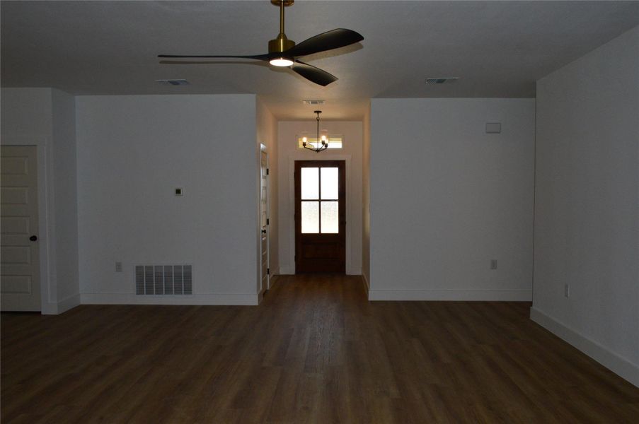 Unfurnished living room featuring dark wood-style flooring, a chandelier, and ceiling fan Unfurnished living room featuring dark wood-style flooring, a chandelier, and ceiling fan