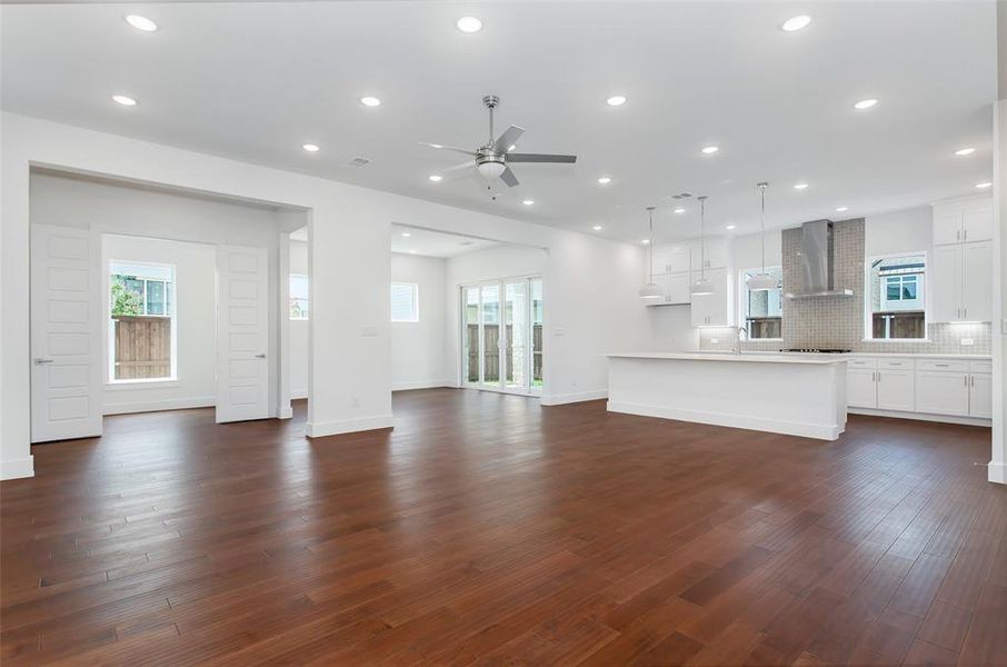 Unfurnished living room featuring dark wood-type flooring, sink, and ceiling fan