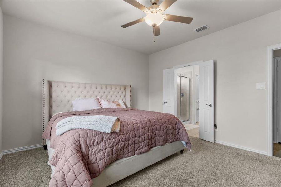 Bedroom with carpet floors, connected bathroom, and a ceiling fan Bedroom with carpet floors, connected bathroom, and a ceiling fan