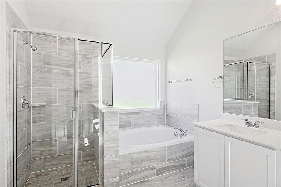 Bathroom featuring vanity, separate shower and tub, and vaulted ceiling