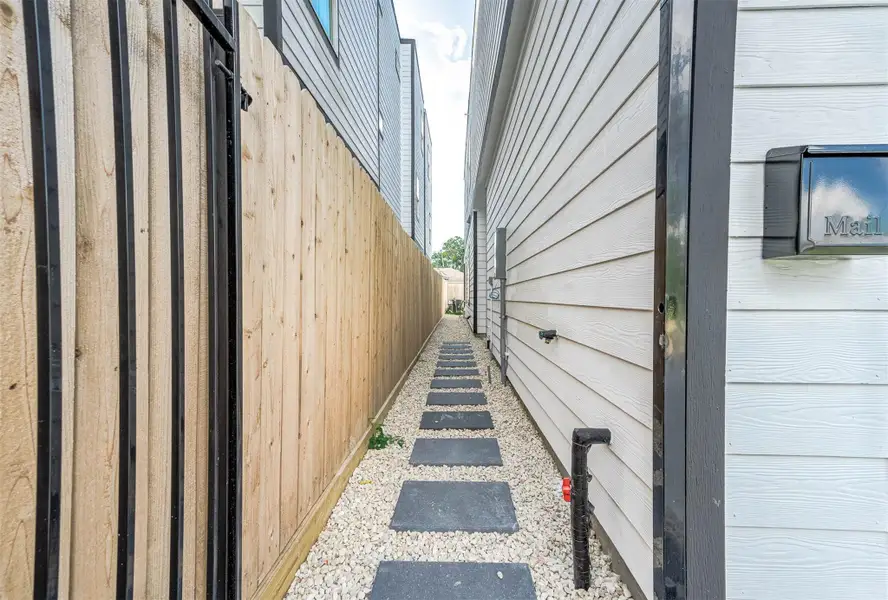 A fully fenced side pathway offers privacy and practical access between the front and backyard.