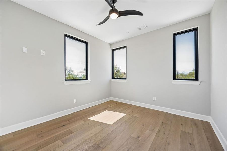 Empty room with light wood finished floors and a ceiling fan Empty room with light wood finished floors and a ceiling fan
