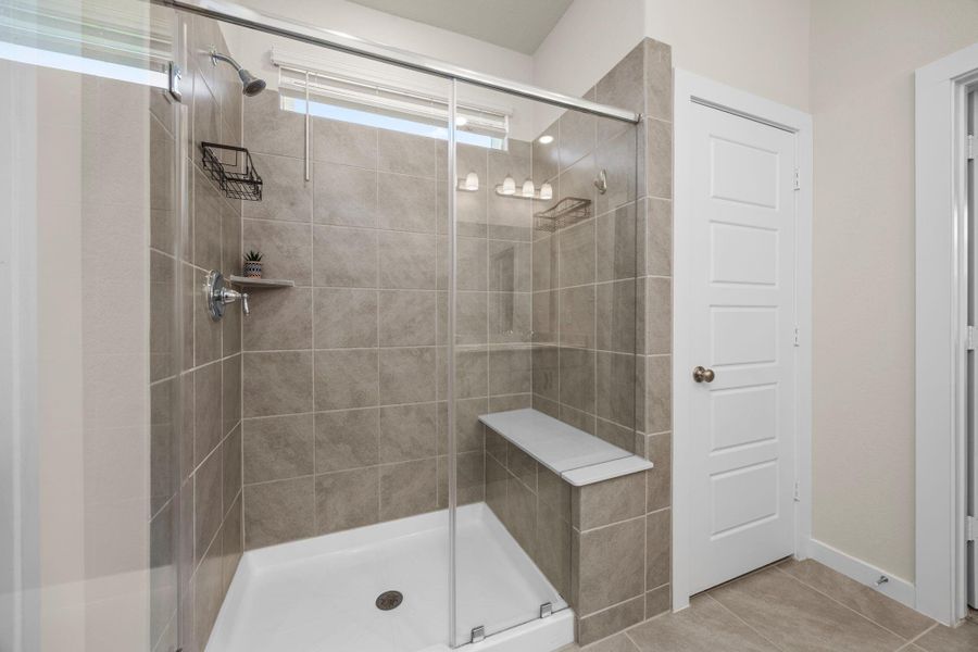 This bright and clean walk-in shower offers a luxurious feel with its stylish tile work and a convenient built-in bench.