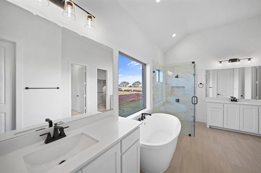 Bathroom with two vanities, a shower stall, a freestanding tub, lofted ceiling, and recessed lighting