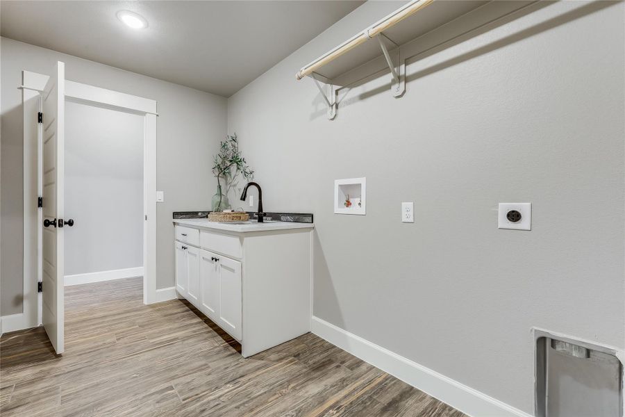 Laundry room with washer hookup, light wood-style floors, hookup for an electric dryer, and cabinet space Laundry room with washer hookup, light wood-style floors, hookup for an electric dryer, and cabinet space
