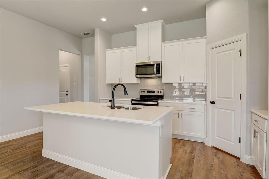 Kitchen with an island with sink, sink, light hardwood / wood-style floors, and appliances with stainless steel finishes