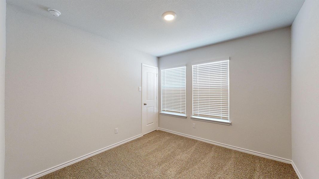 Carpeted empty room featuring baseboards and a smoke detector Carpeted empty room featuring baseboards and a smoke detector