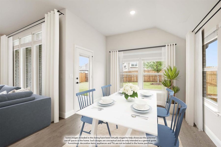 Bright dining area with white table, blue chairs, vaulted ceiling, and large windows overlooking backyard Bright dining area with white table, blue chairs, vaulted ceiling, and large windows overlooking backyard
