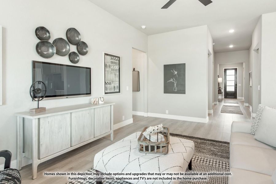 Living room with wall-mounted TV, light wood console, hardwood floors, and ceiling fan opening to hallway Living room with wall-mounted TV, light wood console, hardwood floors, and ceiling fan opening to hallway