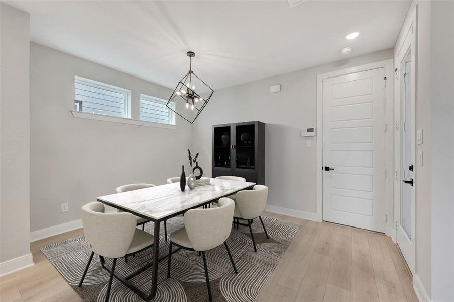 Dining area with light wood-type flooring and a chandelier