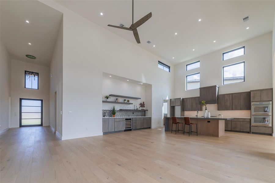 Kitchen with a kitchen bar, a high ceiling, open floor plan, modern cabinets, and a large island with sink