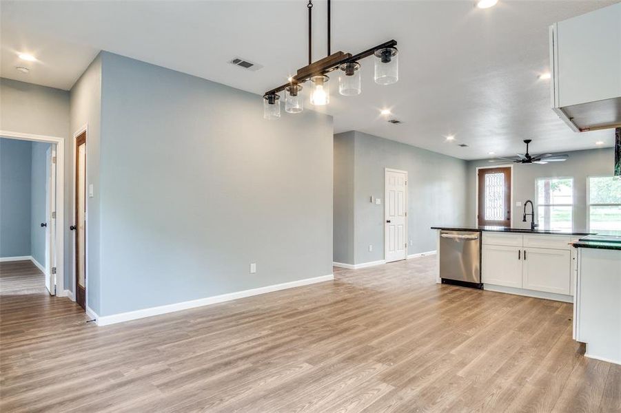 Kitchen with light hardwood / wood-style flooring, white cabinets, sink, stainless steel dishwasher, and ceiling fan