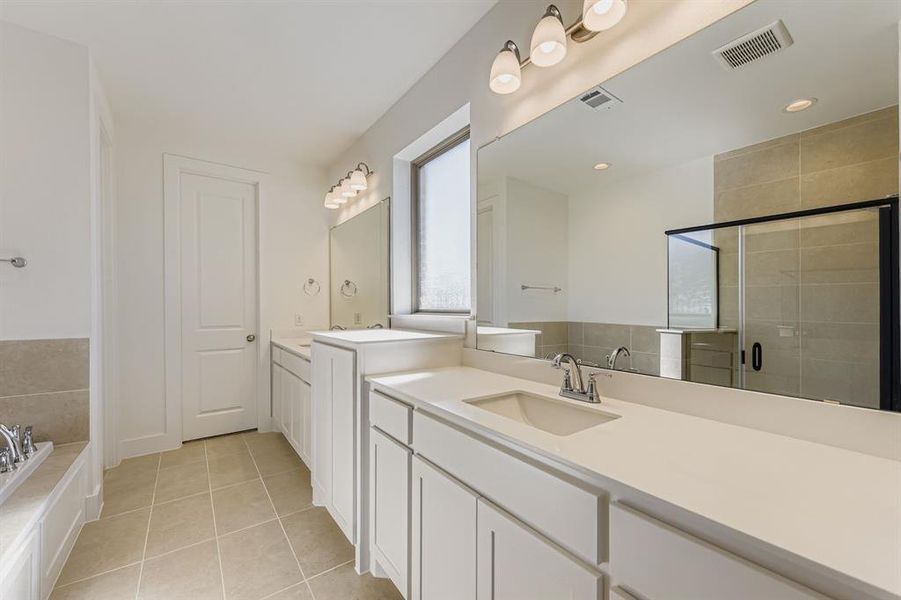 Bathroom with two vanities, light tile patterned flooring, a stall shower, and a bath Bathroom with two vanities, light tile patterned flooring, a stall shower, and a bath