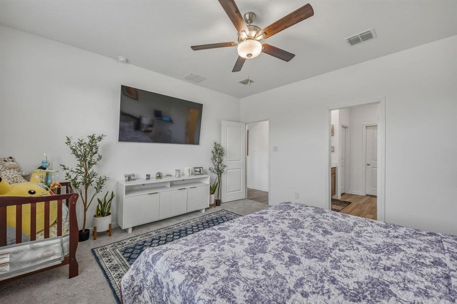 Spacious interior room featuring a ceiling fan with integrated lighting, wood-finish flooring visible through an open doorway, and a crisp white wall palette Spacious interior room featuring a ceiling fan with integrated lighting, wood-finish flooring visible through an open doorway, and a crisp white wall palette