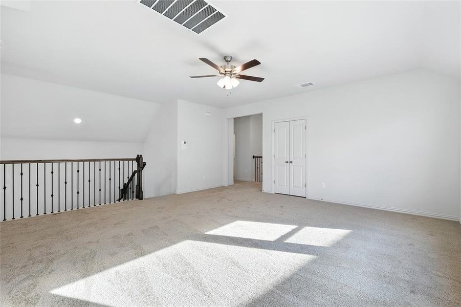 Bonus room with lofted ceiling, light colored carpet, and a ceiling fan