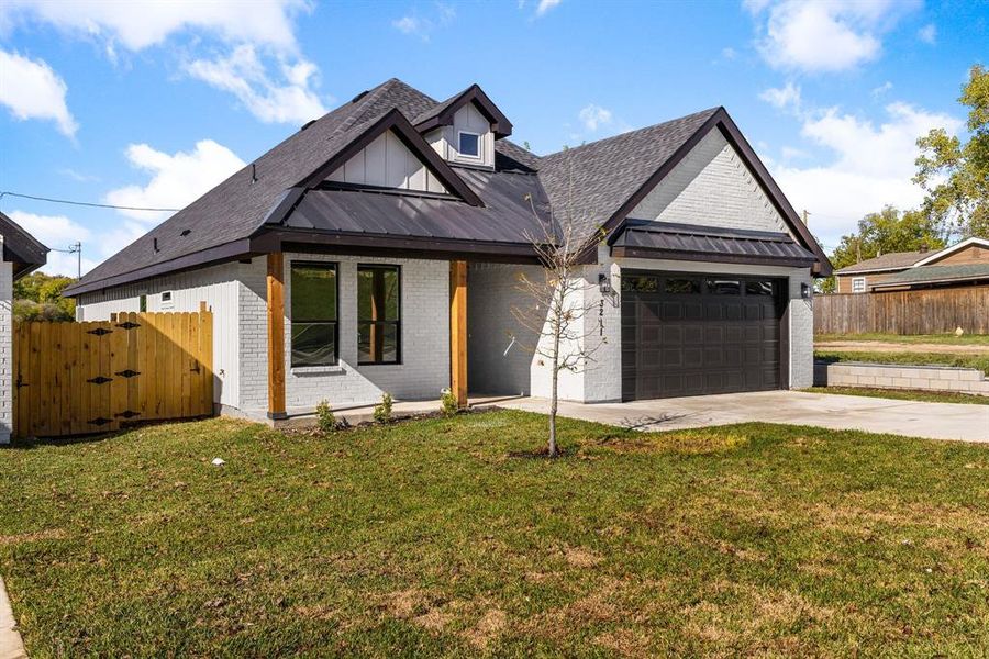 Modern inspired farmhouse featuring a garage and a front lawn