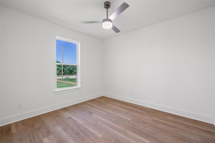 Room with wood-finish flooring, white walls, and a modern ceiling fan with integrated lighting