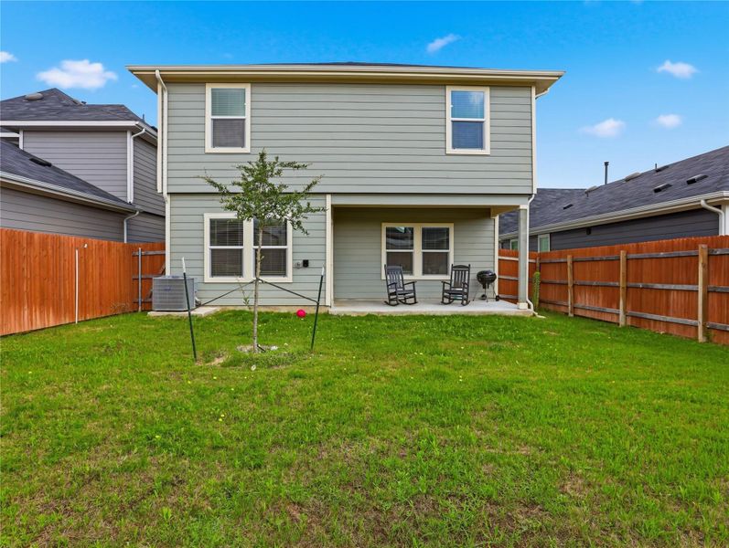 A spacious grassy yard sits framed by protective wood fencing behind this two-story residence. A spacious grassy yard sits framed by protective wood fencing behind this two-story residence.