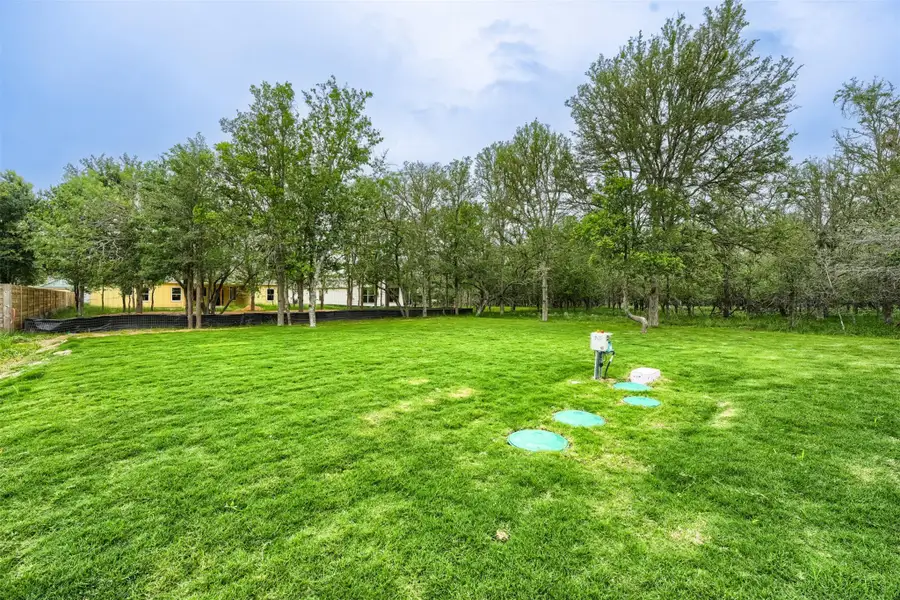 Expansive green lawn with mature trees bordering the perimeter