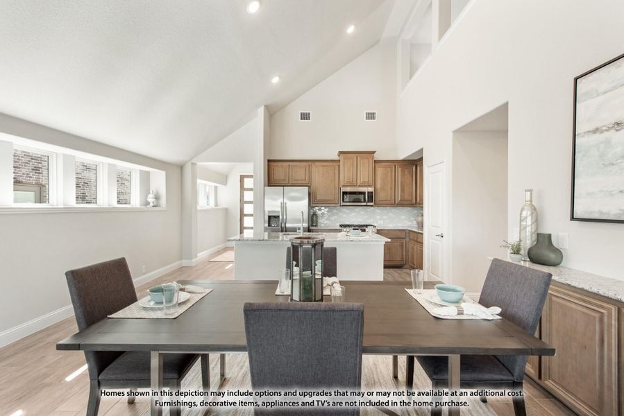 Open dining area with dark wood table flowing into kitchen with vaulted ceiling and stainless appliances Open dining area with dark wood table flowing into kitchen with vaulted ceiling and stainless appliances
