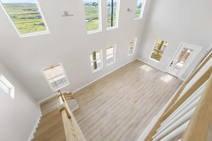 This spacious living area features high ceilings and abundant natural light from multiple windows. The open layout includes light wood flooring and a modern staircase, creating a bright and inviting atmosphere. This spacious living area features high ceilings and abundant natural light from multiple windows. The open layout includes light wood flooring and a modern staircase, creating a bright and inviting atmosphere.