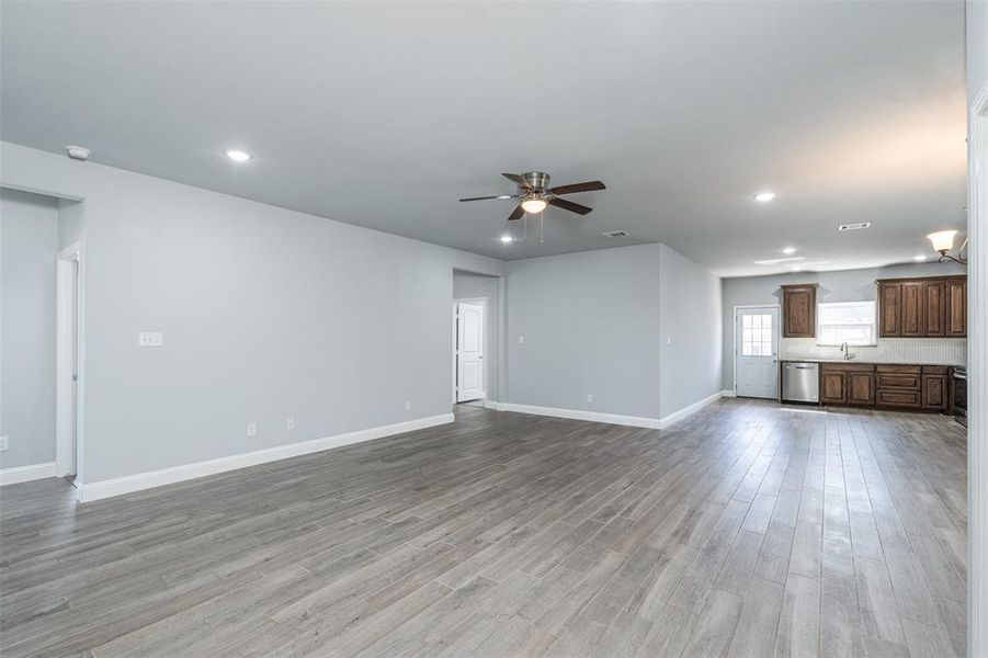 Unfurnished living room with baseboards, a ceiling fan, light wood-style floors, a sink, and recessed lighting