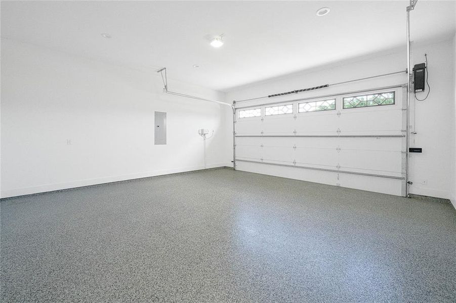 Garage featuring electric panel and baseboards