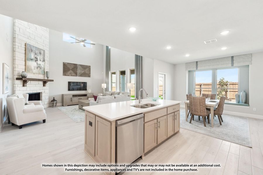 Open-concept kitchen with island and sink, flowing into living room with stone fireplace and dining area