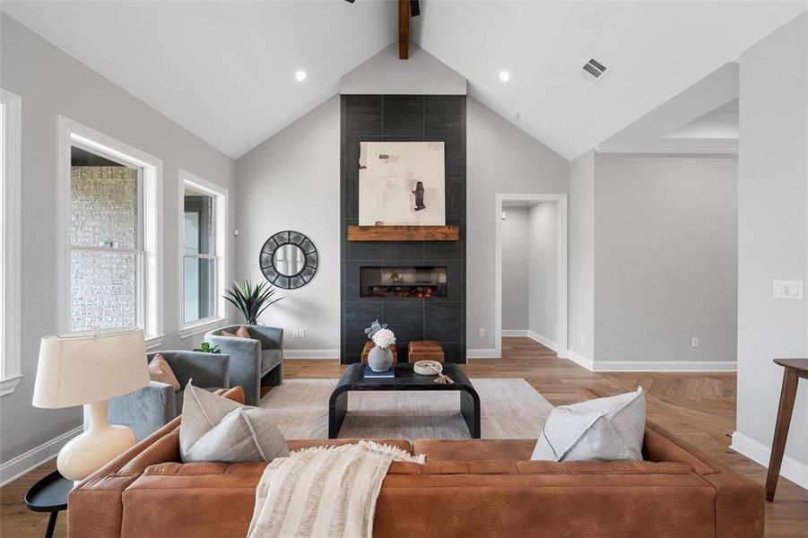 Living area with beamed ceiling, wood finished floors, high vaulted ceiling, a tiled fireplace, and recessed lighting Living area with beamed ceiling, wood finished floors, high vaulted ceiling, a tiled fireplace, and recessed lighting
