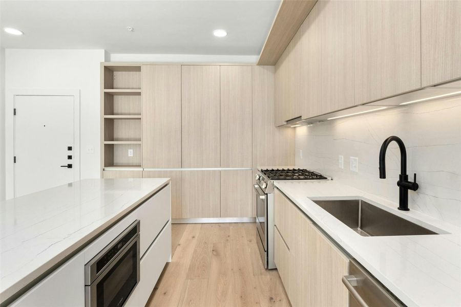 Kitchen with stainless steel appliances, modern cabinets, light wood-style flooring, and recessed lighting