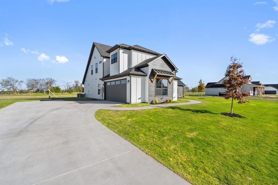 View of side of home with a lawn, driveway, an attached garage, and board and batten siding View of side of home with a lawn, driveway, an attached garage, and board and batten siding