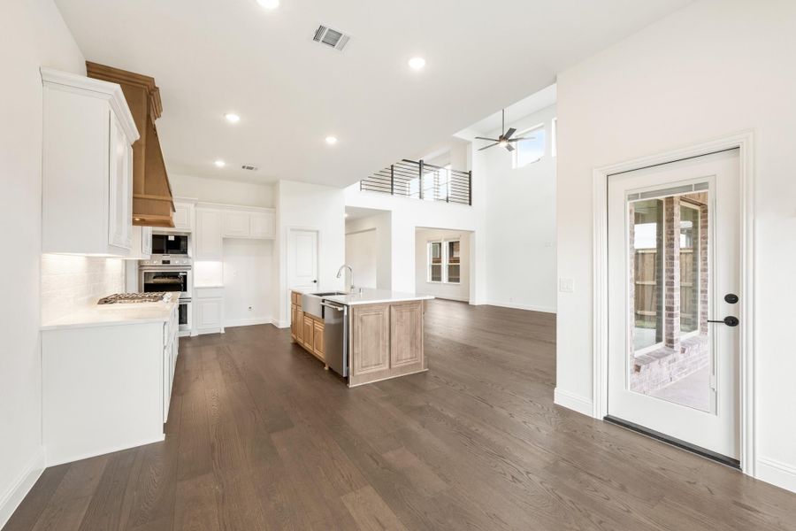 Open-concept kitchen with white cabinets, wood island, dark hardwood floors, and high ceilings