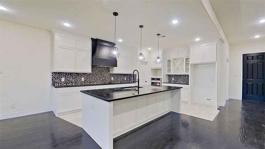 Kitchen with decorative backsplash, white cabinetry, light wood-style floors, and an island with sink Kitchen with decorative backsplash, white cabinetry, light wood-style floors, and an island with sink