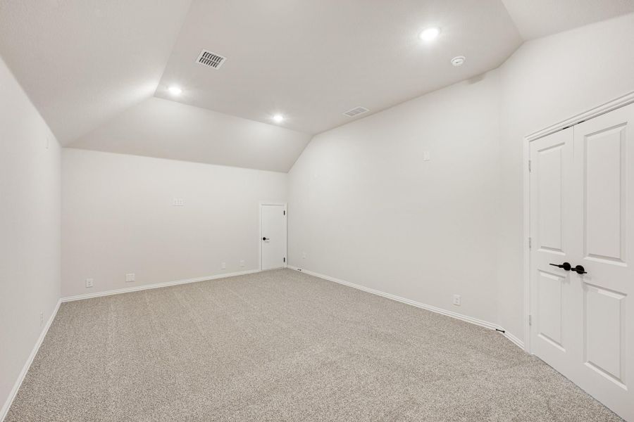 Empty bedroom with vaulted ceiling, recessed lighting, carpet flooring, and white walls Empty bedroom with vaulted ceiling, recessed lighting, carpet flooring, and white walls