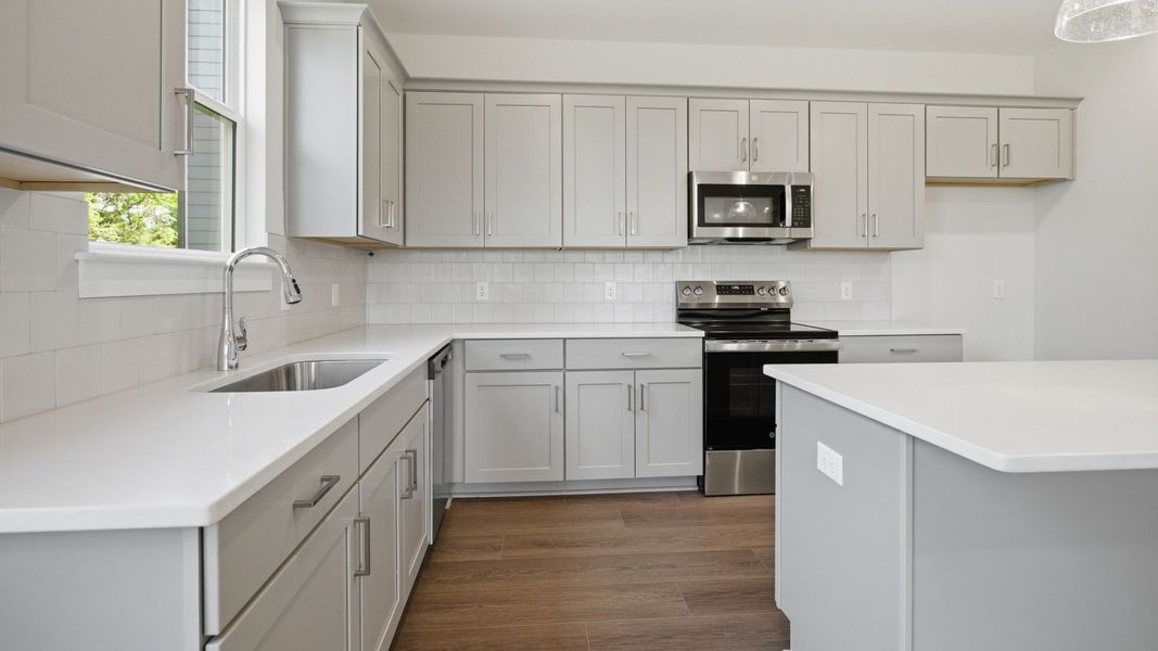 Kitchen with light cabinetry, quartz countertops, and tile backsplash Kitchen with light cabinetry, quartz countertops, and tile backsplash