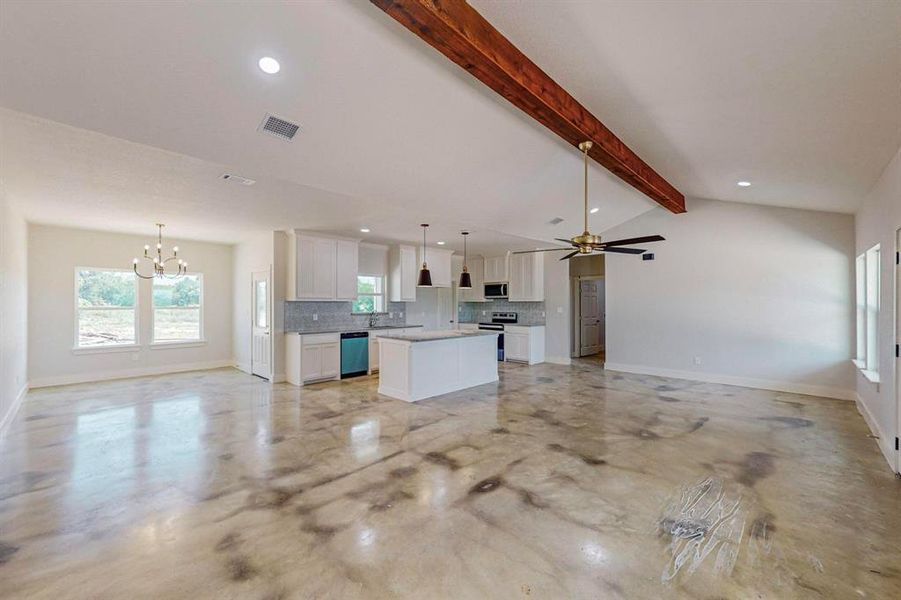 Unfurnished living room featuring lofted ceiling with beams and ceiling fan with notable chandelier