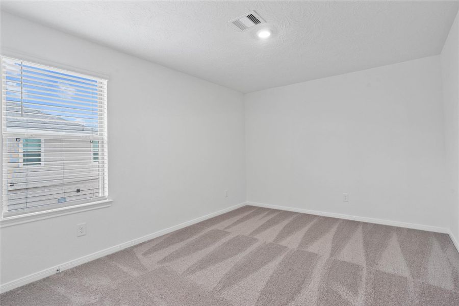 This secondary bedroom offers comfort and style with plush carpeting, neutral paint tones, recessed lighting, a large window with blinds, and a generously sized closet.