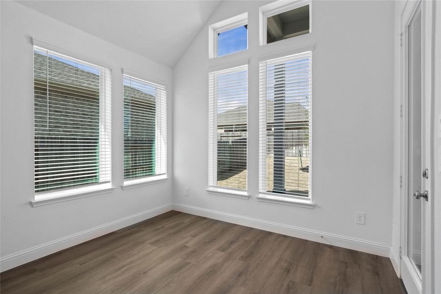The breakfast area is filled with natural light and features high ceilings, recessed lighting, expansive windows with fitted blinds, and an access door to the back covered patio.