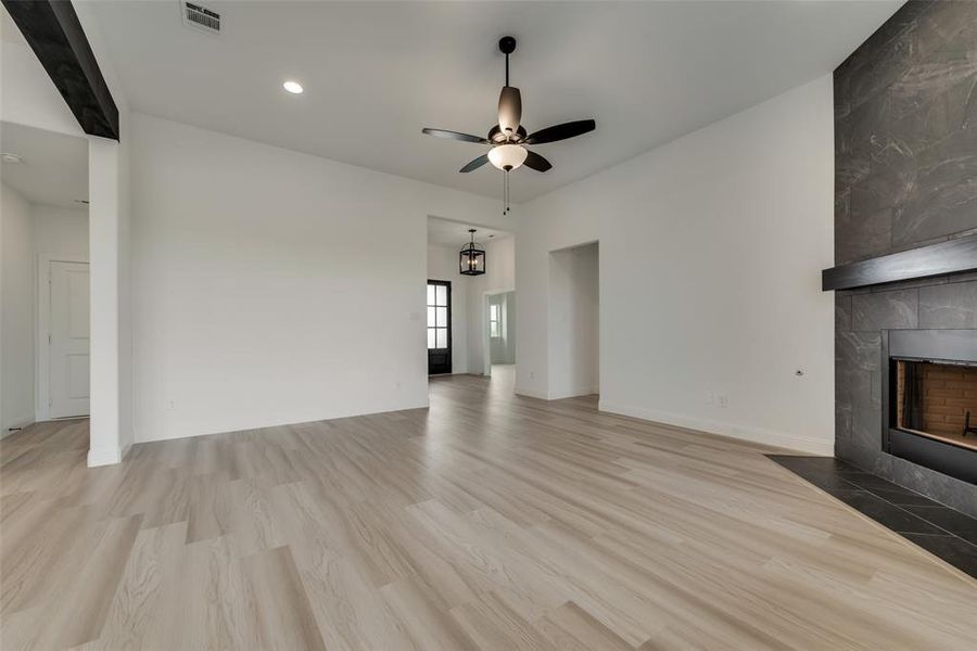 Unfurnished living room with ceiling fan, a tile fireplace, and hardwood / wood-style floors