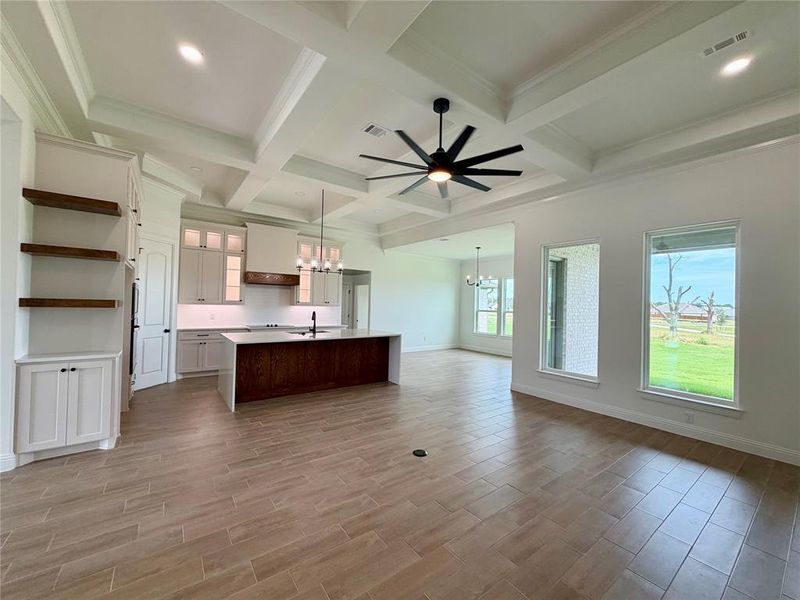 Spacious open-concept interior featuring light wood-finish flooring, a coffered ceiling, and recessed lighting
