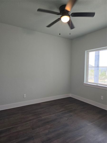Unfurnished room with dark wood-style flooring and a ceiling fan