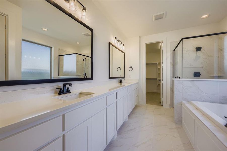Full bathroom with a marble finish shower, a bath, double vanity, a spacious closet, and recessed lighting Full bathroom with a marble finish shower, a bath, double vanity, a spacious closet, and recessed lighting