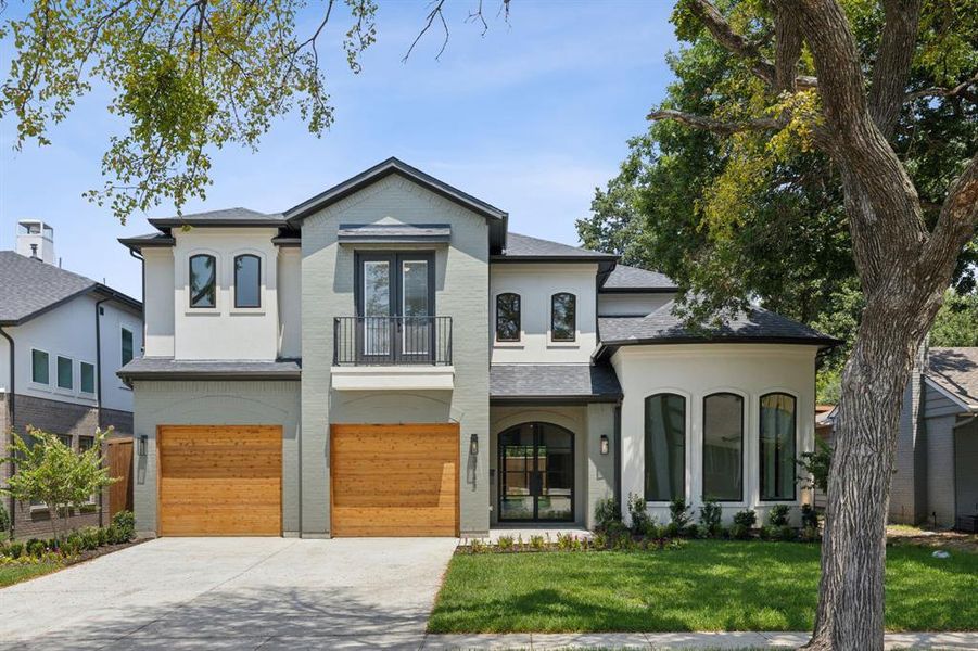 View of front facade featuring a front lawn, a garage, and a balcony