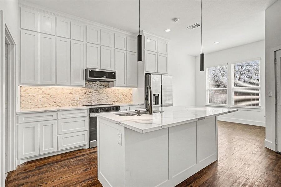Kitchen featuring decorative backsplash, stainless steel appliances, white cabinetry, and light stone countertops
