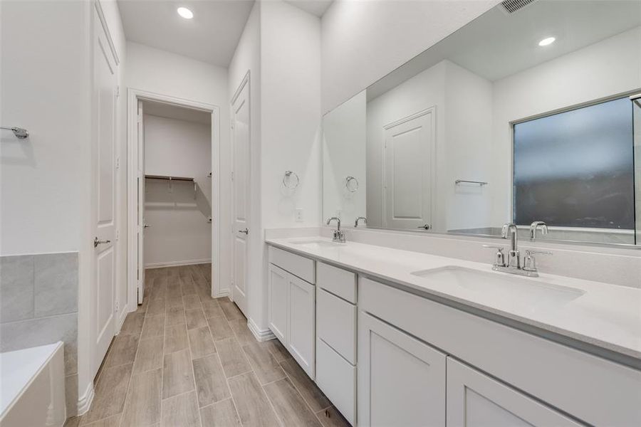 Bathroom featuring dual bowl vanity and a bath