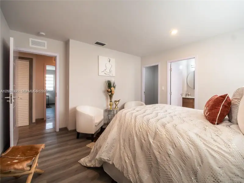 Room featuring wood-finish flooring, neutral wall paint, and double-entry doors including a louvered closet door